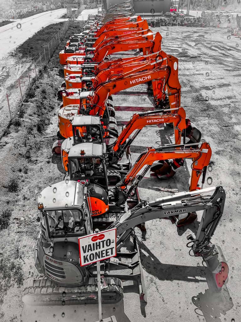Rivissä olevia käytettyjä kaivinkoneita, etualalla "Vaihtokoneet" -kyltti. Kuvassa näkyy muun muassa Hitachi- ja Yanmar-merkkisiä koneita.