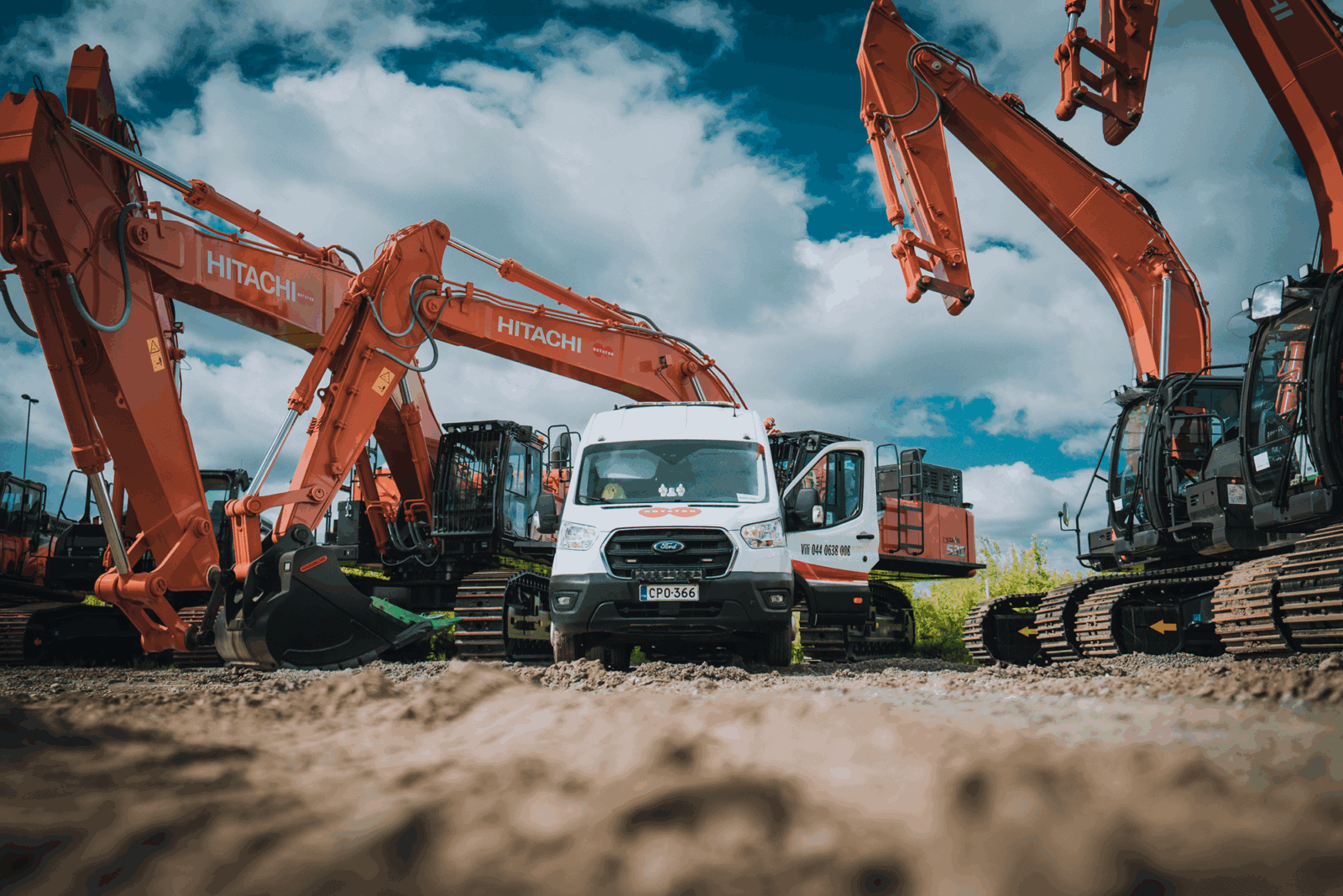Hitachi-kaivinkoneita ja Rotatorin huoltoauto työmaalla kirkkaan taivaan alla.